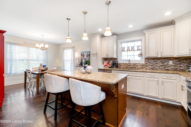 kitchen with a wealth of natural light, dark hardwood / wood-style flooring, a kitchen island, and hanging light fixtures