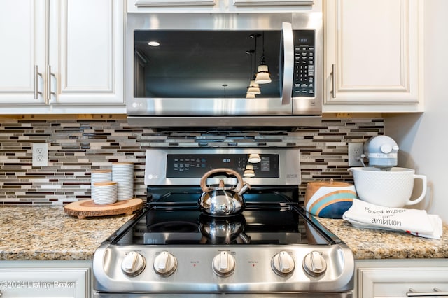 kitchen featuring white cabinets, light stone counters, stainless steel appliances, and tasteful backsplash