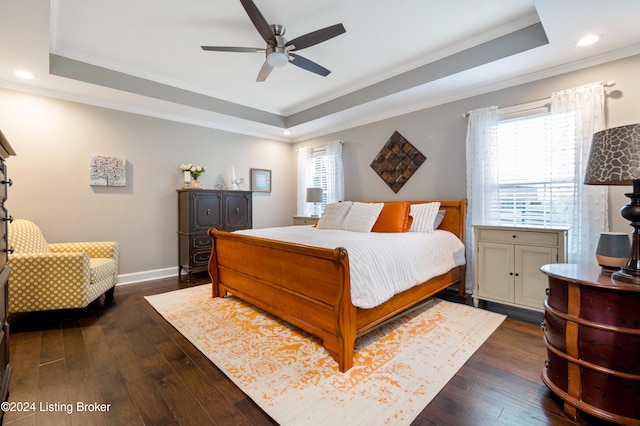 bedroom with a tray ceiling, dark hardwood / wood-style floors, crown molding, and ceiling fan