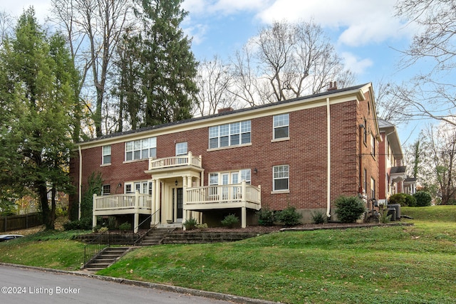 multi unit property featuring a front yard, a balcony, and cooling unit