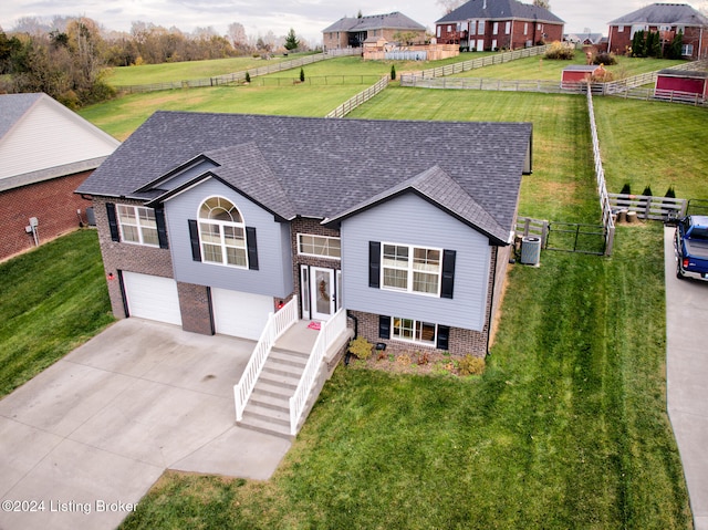 bi-level home with cooling unit, a front lawn, and a garage