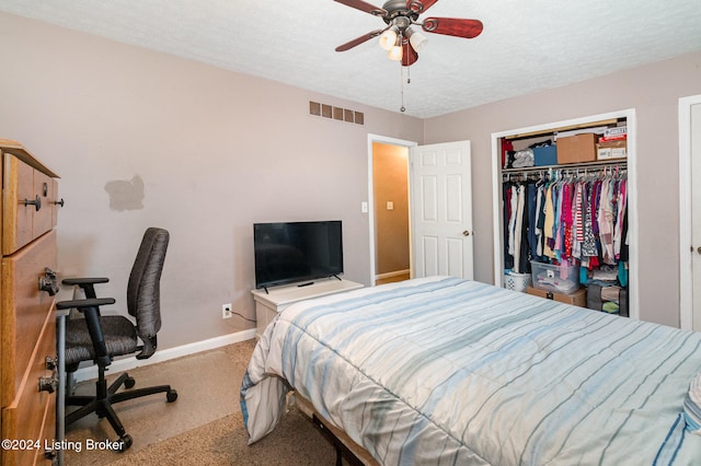 bedroom featuring a textured ceiling, carpet floors, a closet, and ceiling fan