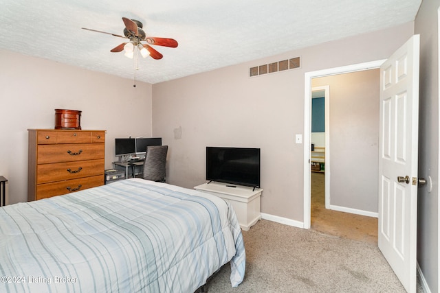 bedroom with ceiling fan, light colored carpet, and a textured ceiling