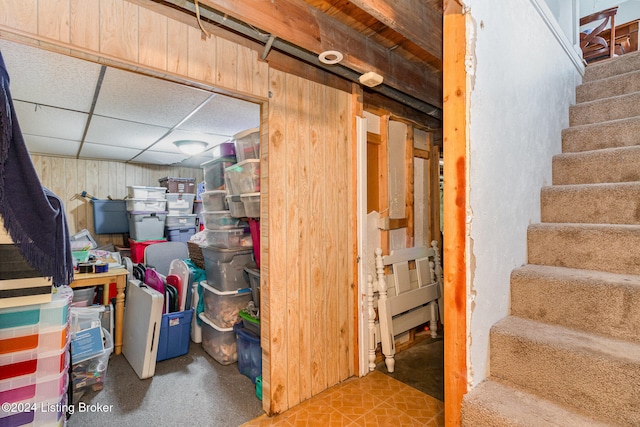 basement with a paneled ceiling and wooden walls