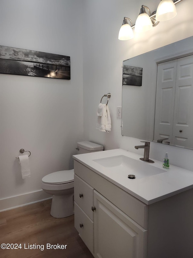 bathroom with baseboards, vanity, toilet, and wood finished floors