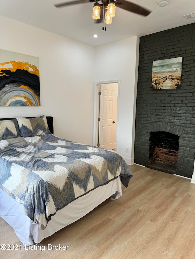 bedroom with ceiling fan, a fireplace, and light wood-type flooring