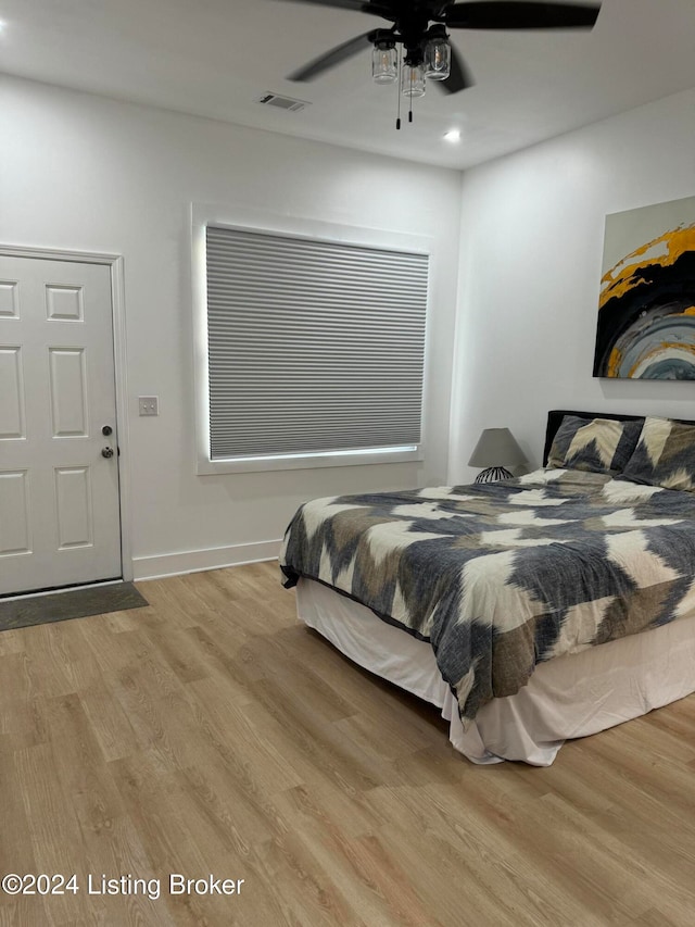 bedroom featuring a ceiling fan, wood finished floors, visible vents, and baseboards