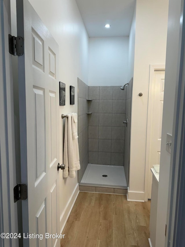 full bathroom with a tile shower, wood finished floors, and vanity