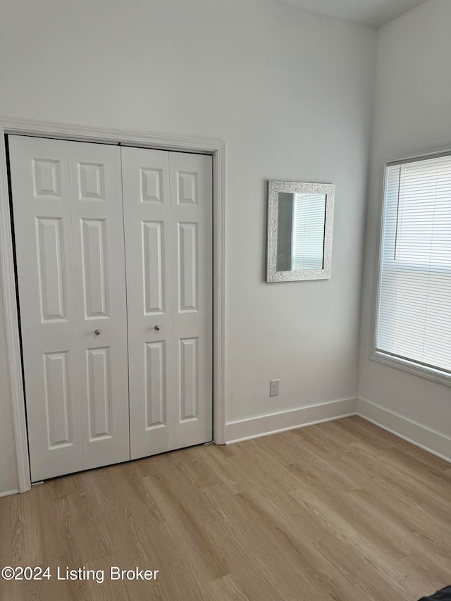 unfurnished bedroom with light wood-type flooring, baseboards, and a closet