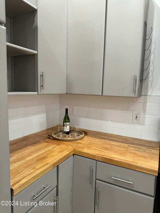 kitchen featuring decorative backsplash, gray cabinets, and wooden counters