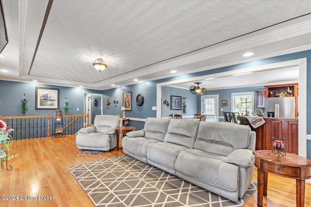 living room featuring a raised ceiling, hardwood / wood-style floors, a textured ceiling, and ornamental molding