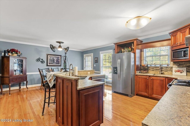 kitchen with appliances with stainless steel finishes, light hardwood / wood-style flooring, a healthy amount of sunlight, and sink