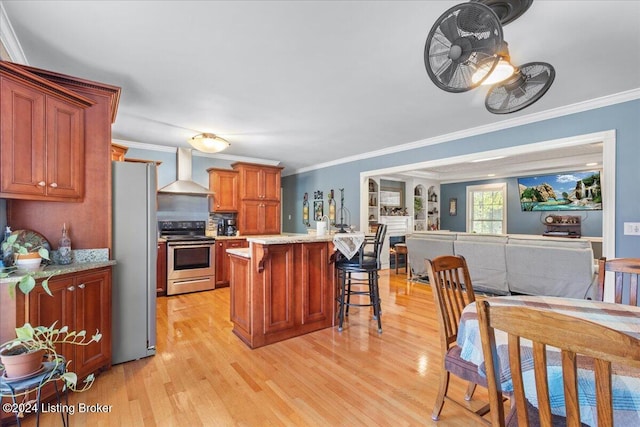 kitchen with crown molding, wall chimney exhaust hood, light wood-type flooring, and appliances with stainless steel finishes