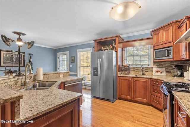 kitchen featuring backsplash, sink, light wood-type flooring, ornamental molding, and appliances with stainless steel finishes