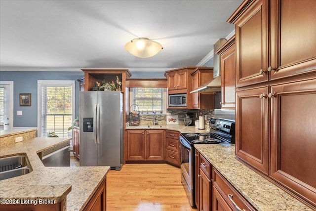 kitchen with plenty of natural light, light wood-type flooring, light stone countertops, and stainless steel appliances