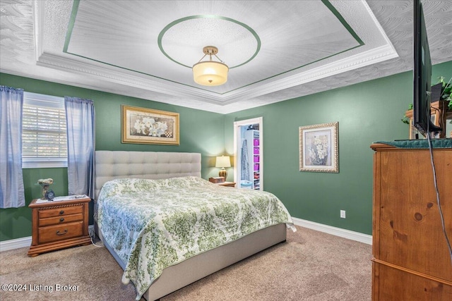 bedroom with a raised ceiling, crown molding, and carpet floors