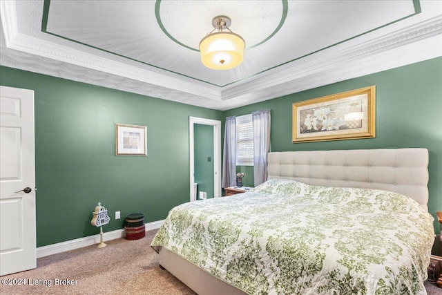 carpeted bedroom featuring a tray ceiling and ornamental molding