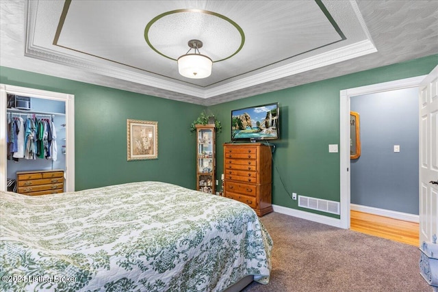 bedroom with a tray ceiling, a closet, carpet, and a textured ceiling