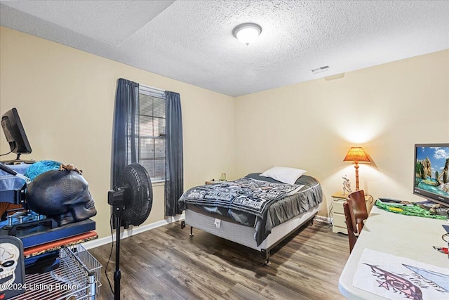 bedroom with dark hardwood / wood-style floors and a textured ceiling