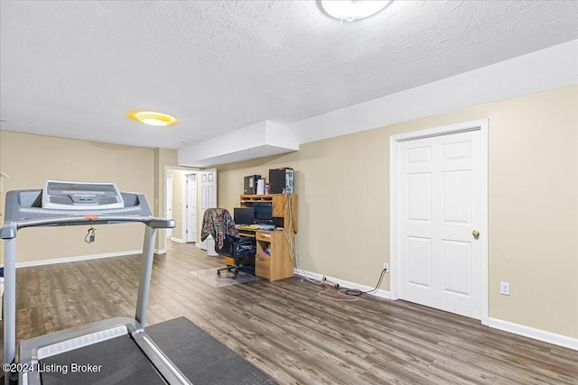 exercise room with wood-type flooring and a textured ceiling