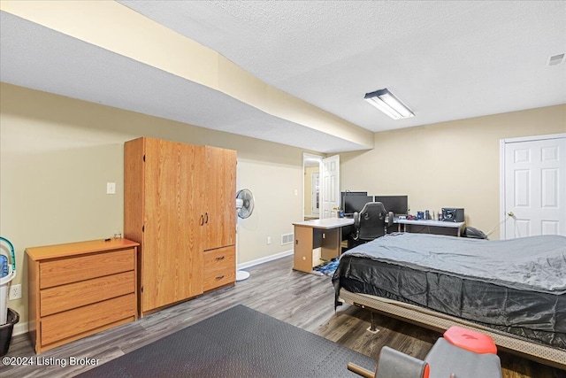 bedroom with dark hardwood / wood-style floors and a textured ceiling