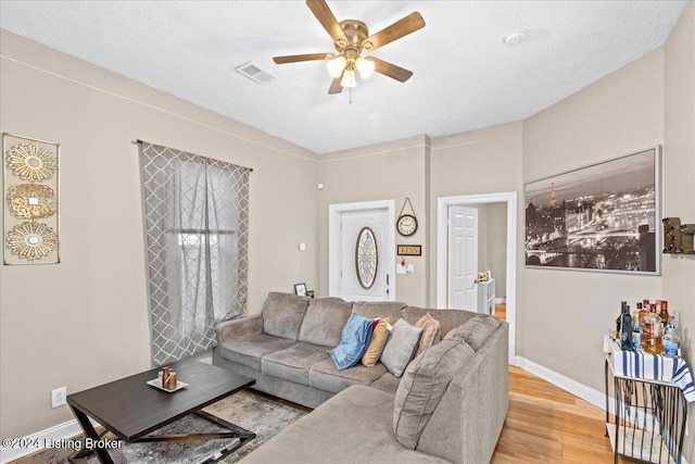 living room with ceiling fan, light hardwood / wood-style floors, and a textured ceiling