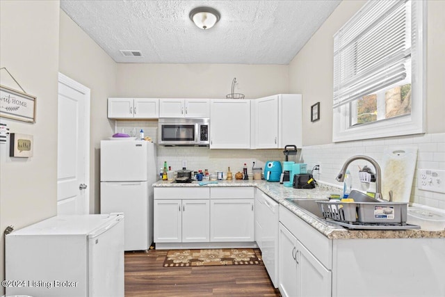 kitchen with a textured ceiling, white cabinets, dark wood-type flooring, and white appliances