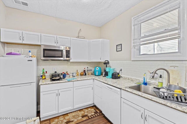 kitchen featuring dark hardwood / wood-style flooring, white appliances, a textured ceiling, sink, and white cabinets