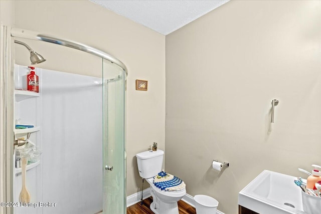 bathroom with vanity, a shower with door, hardwood / wood-style flooring, toilet, and a textured ceiling