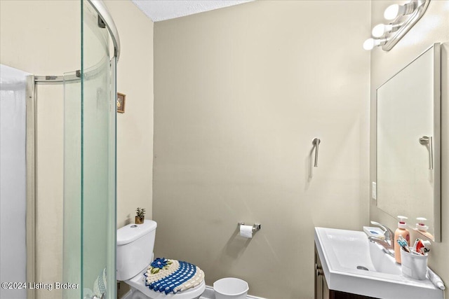 bathroom with a textured ceiling, vanity, toilet, and a shower with shower door