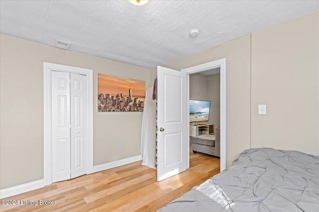 bedroom featuring a closet, wood-type flooring, and a textured ceiling