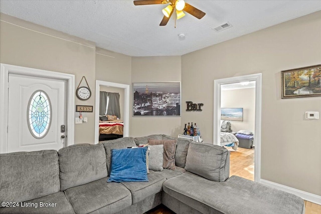 living room featuring hardwood / wood-style floors, ceiling fan, and a textured ceiling