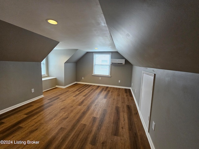 additional living space featuring an AC wall unit, vaulted ceiling, and dark hardwood / wood-style floors