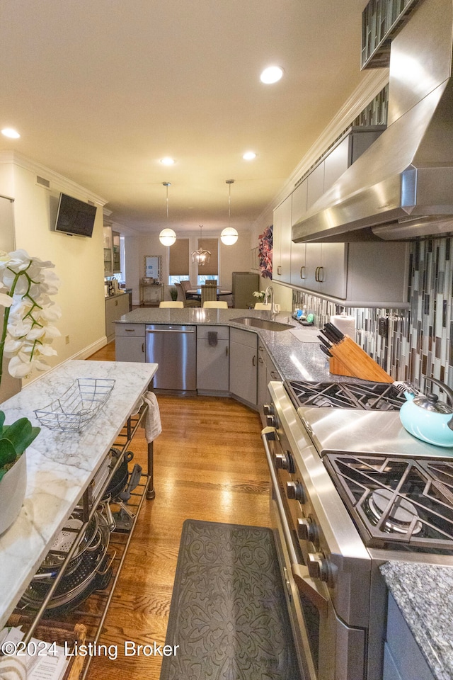 kitchen with gray cabinetry, tasteful backsplash, crown molding, appliances with stainless steel finishes, and hardwood / wood-style flooring