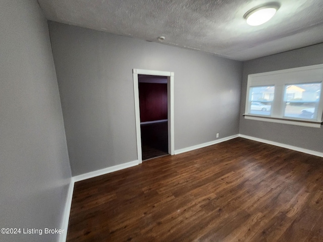 spare room featuring a textured ceiling and dark wood-type flooring