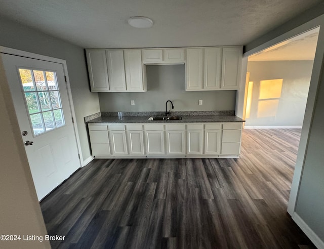 kitchen featuring dark stone countertops, dark hardwood / wood-style flooring, white cabinetry, and sink