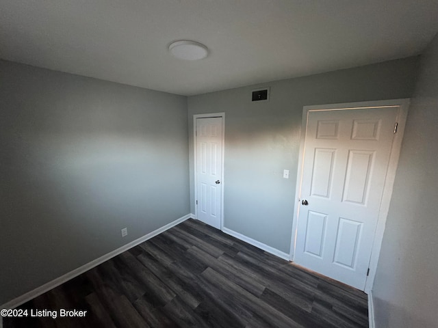 unfurnished bedroom featuring a closet and dark hardwood / wood-style floors