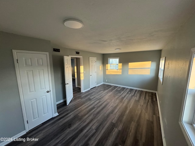 unfurnished bedroom featuring a textured ceiling and dark wood-type flooring