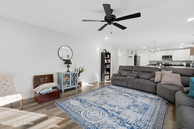 living room with light hardwood / wood-style flooring and ceiling fan with notable chandelier