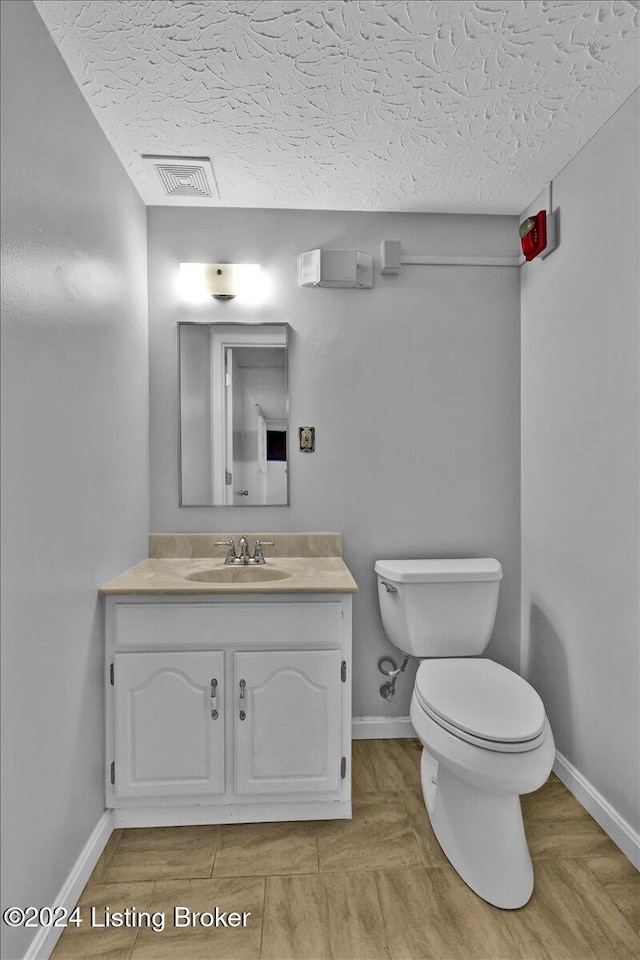 bathroom featuring a textured ceiling, vanity, and toilet