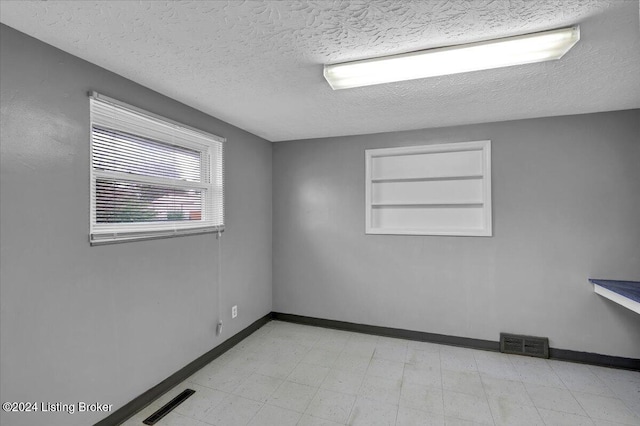 empty room with built in shelves and a textured ceiling