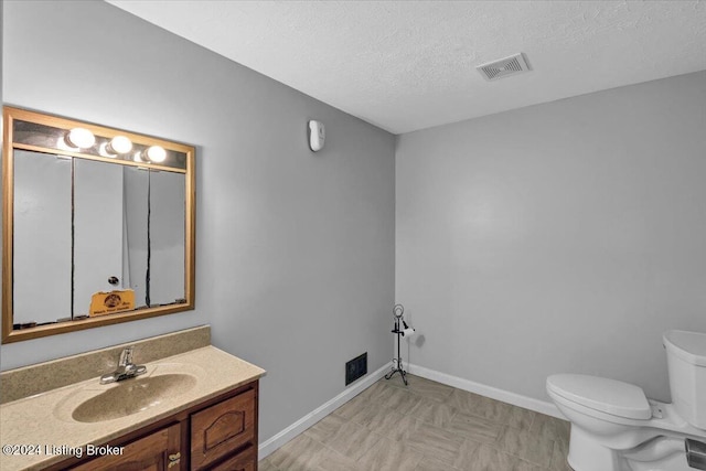 bathroom featuring vanity, toilet, and a textured ceiling