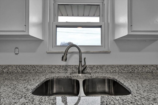 interior details with light stone countertops, sink, and white cabinets