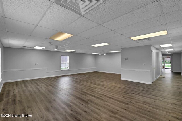 spare room with a paneled ceiling and dark hardwood / wood-style floors