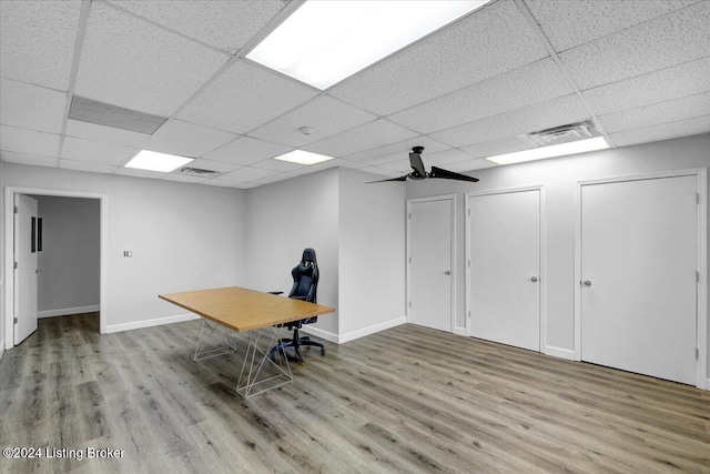 unfurnished office with a paneled ceiling, ceiling fan, and light wood-type flooring