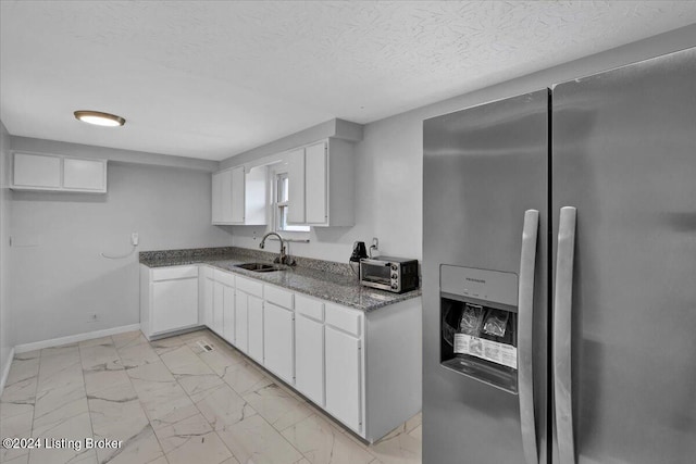 kitchen with white cabinetry, stainless steel fridge with ice dispenser, sink, and a textured ceiling