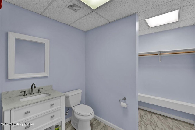 bathroom with vanity, toilet, and a drop ceiling