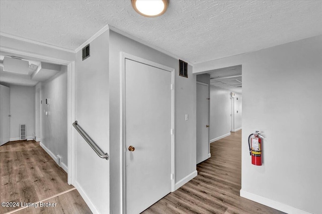 corridor featuring a textured ceiling and light hardwood / wood-style flooring