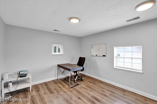 office space with a textured ceiling and light hardwood / wood-style flooring