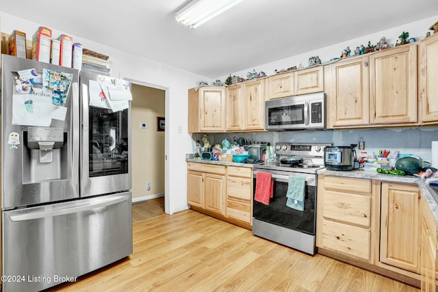 kitchen with backsplash, light brown cabinets, stainless steel appliances, and light wood-type flooring